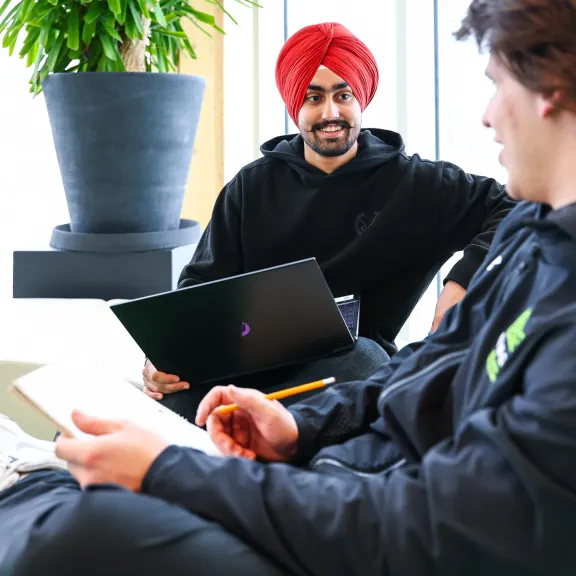 Two students studying together in a brightly lit room.
