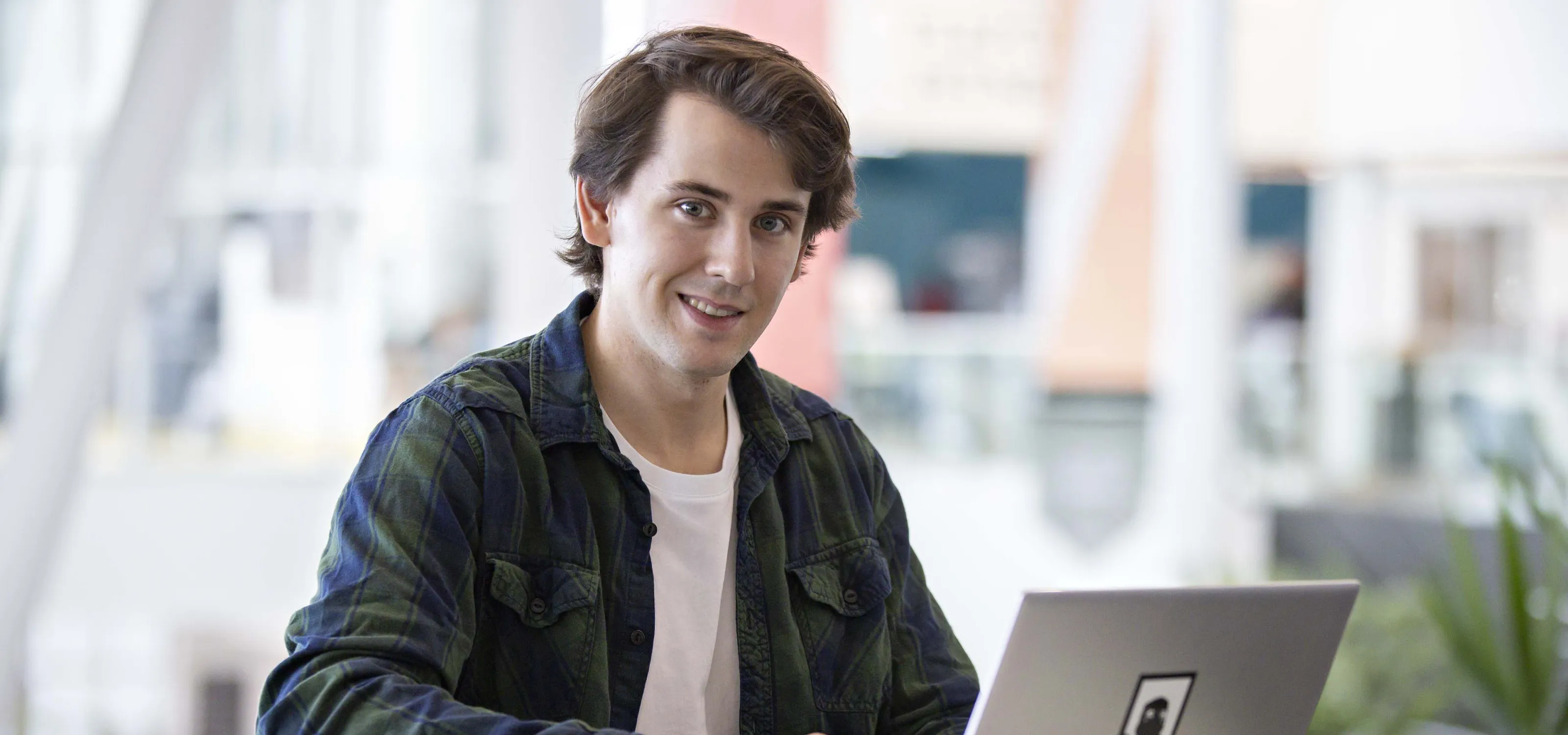 Young man with open laptop looking at the camera.