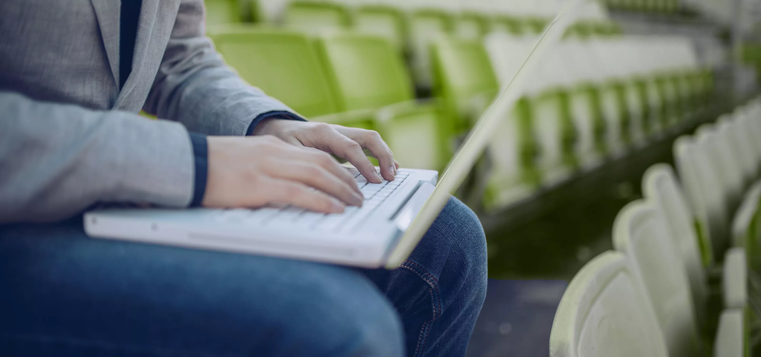 Person on a laptop seated in gymnasium seating.